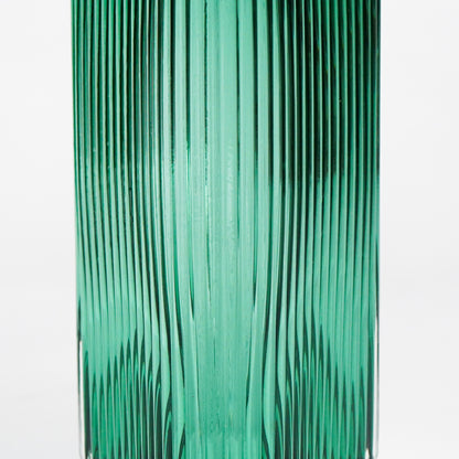 Closeup image of long green luxury glass vase for elegant tabletop decor styling highlighting smooth reflective glass finish.