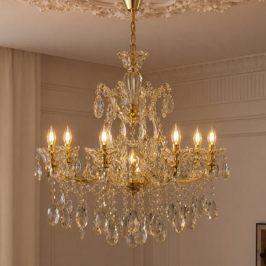 An ornate gold and clear crystal chandelier hanging from a decorative ceiling in an elegant room with beige walls and curtains.