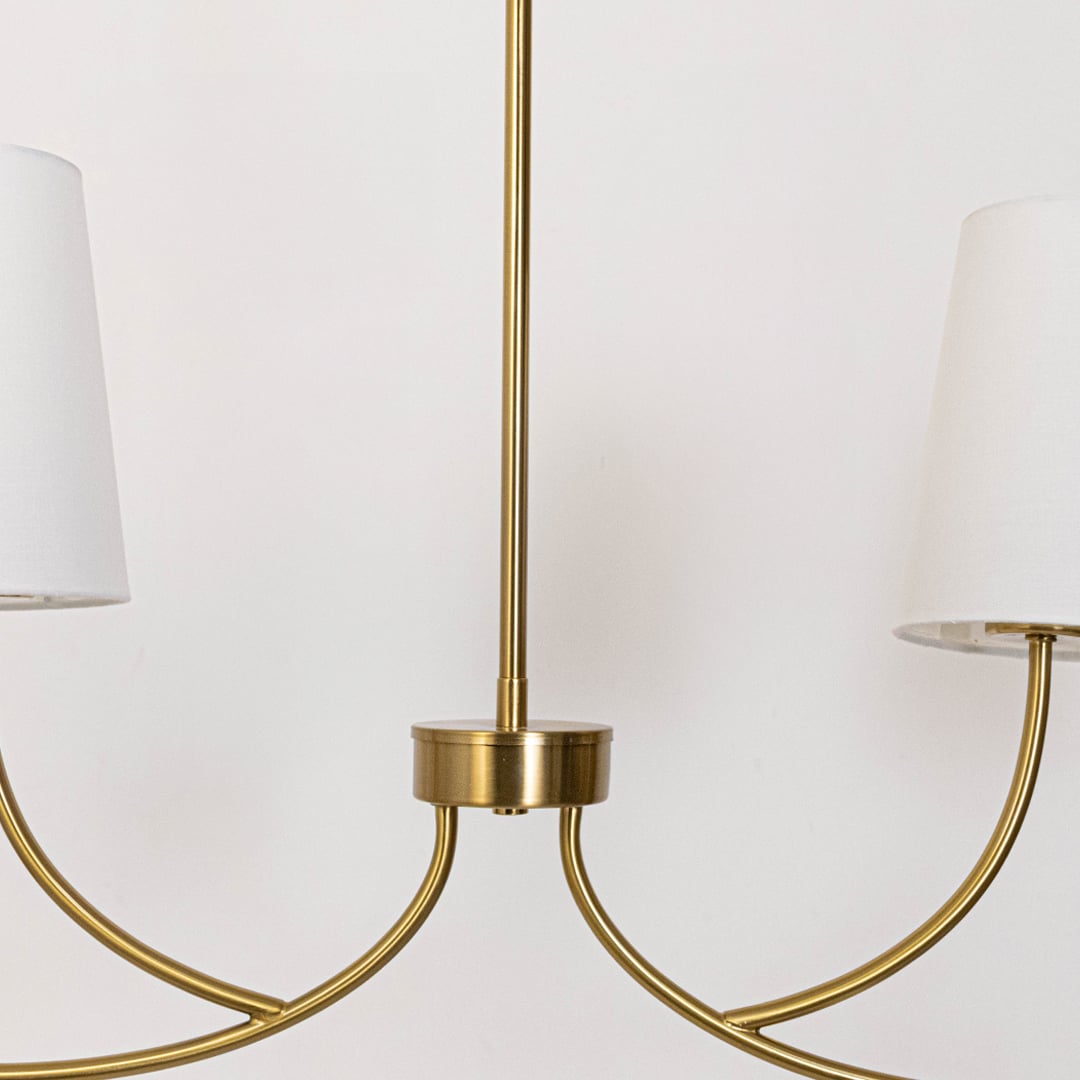 Closeup of gold metal chandelier arm with smooth curved form and premium finish highlighting elegant craftsmanship for luxury lighting.