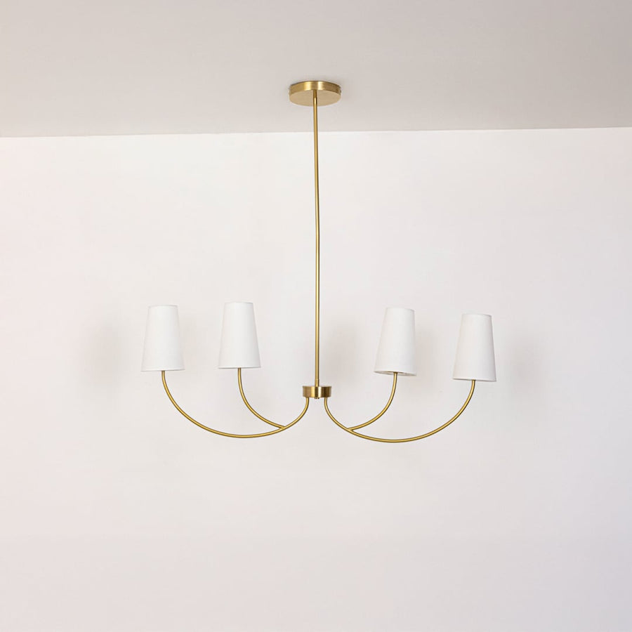 Contemporary brass gold five arm chandelier with white fabric cone shades and rod turned off displayed on white background.