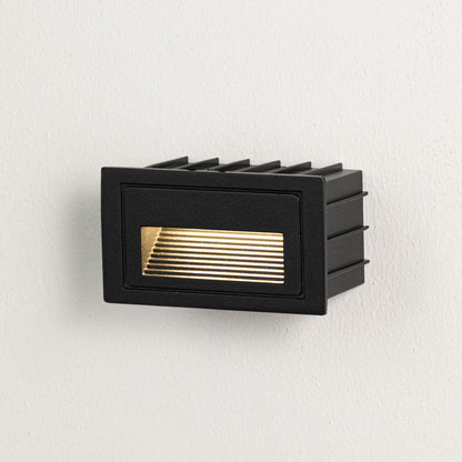Black metal outdoor wall light on white background with louvered warm lighting for minimalist patio decor.