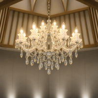 Lifestyle image of large gold metal candle style chandelier for luxury living room decor styling with elegant crystal detailing.