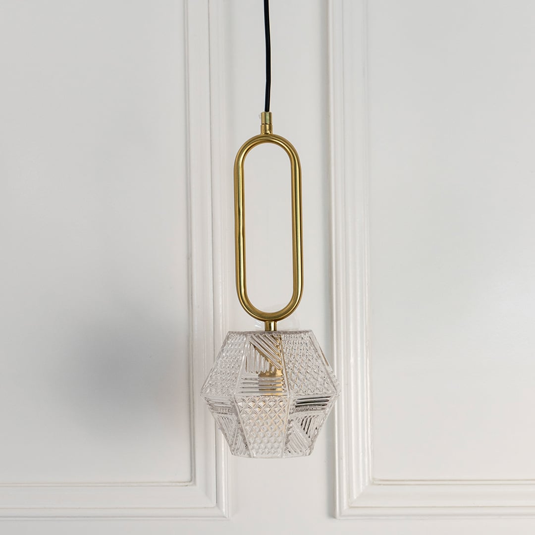 Gold metal pendant light with geometric crystal shade crafted for luxurious contemporary interiors.
