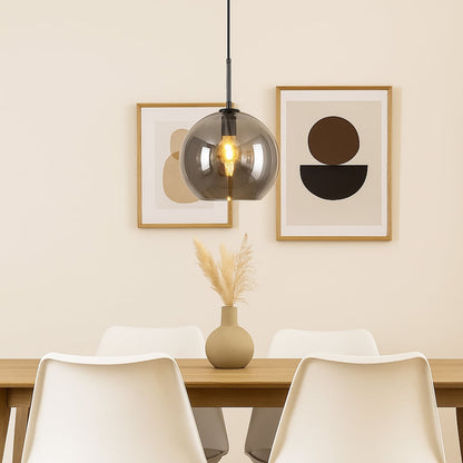 Pendant light with smoked glass shade and metal fitting hanging above dining table creating soft illumination and modern dining room style.