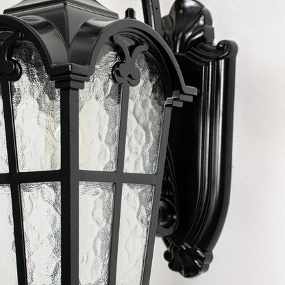 Closeup view of black metal wall lantern highlighting textured glass panels curved arm design and premium outdoor construction.