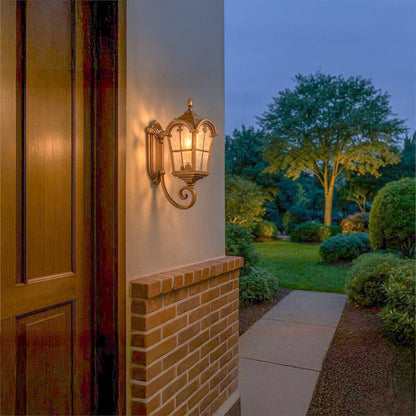 Elegant outdoor wall light in bronze metal with textured glass glowing warmly on a garden entryway enhancing exterior decor beautifully.
