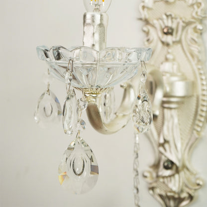 Silver wall sconce with clear glass teardrop crystal drops and a scalloped glass bowl shade, shown close-up against a light neutral background.