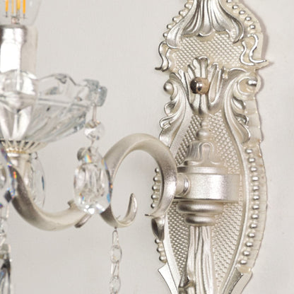 Closeup of silver wall light showing crystal droplets and ornate metal detailing for premium interior lighting accents.