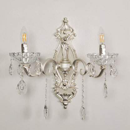 Closeup of silver double wall light showing ornate metal curves and crystal droplets for premium interior lighting detail.