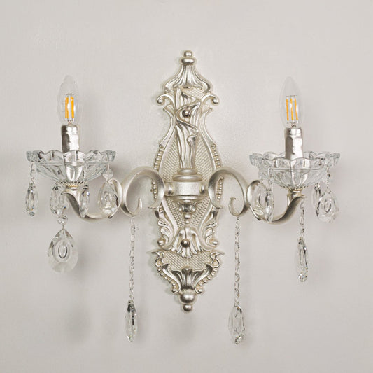 Closeup of silver double wall light showing ornate metal curves and crystal droplets for premium interior lighting detail.