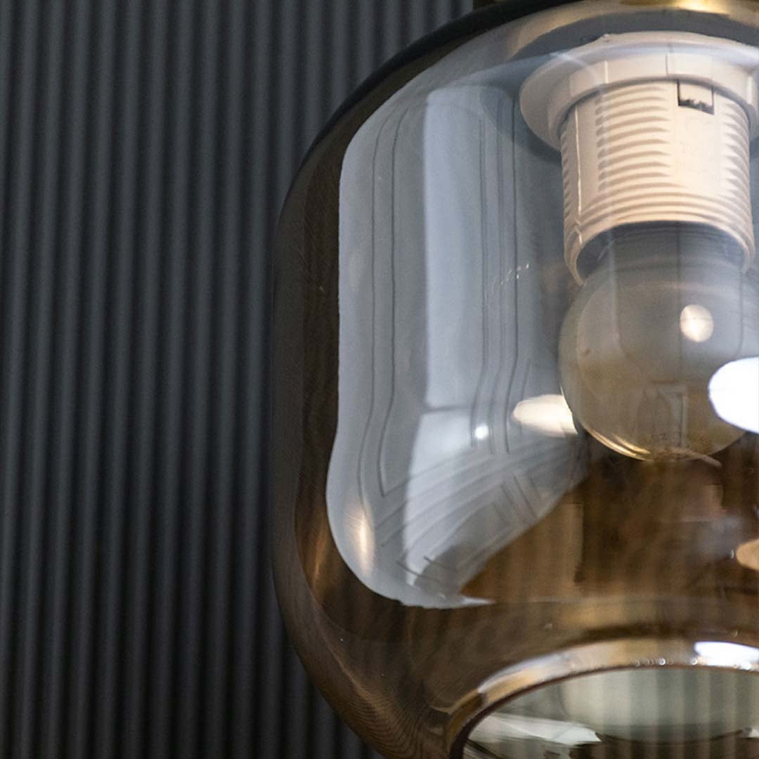 A closeup view of the gold and amber pendant light showing the reflective tinted glass shade and polished metal top ideal for modern interiors.