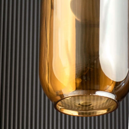A closeup view of the gold and amber pendant light showing the reflective tinted glass and polished metal top ideal for warm modern interiors.