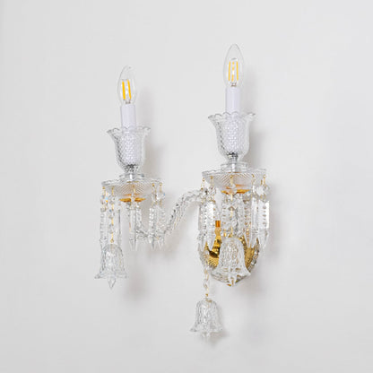 Double arm crystal wall light with gold base and decorative glass shades turned off on white background.
