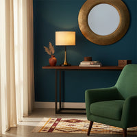 Table lamp with fabric shade placed on console table below round wall mirror creating soft ambient lighting for modern living room decor.