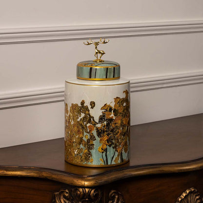 Round ceramic jar in white and teal with embossed golden tree design and deer topper perfect for modern interiors.