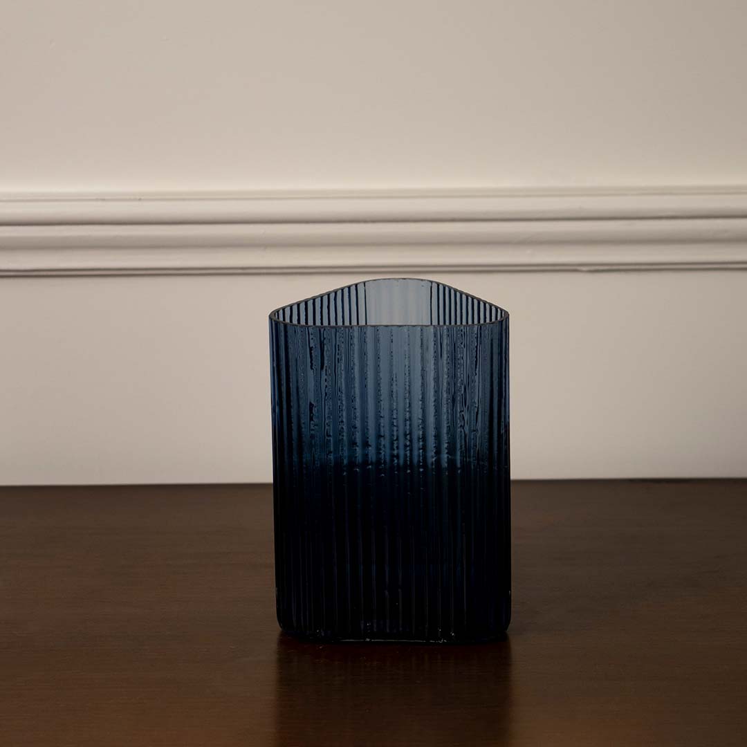 Deep blue ribbed glass vase for sophisticated home decor displays creating a vibrant pop of color on bedside table.
