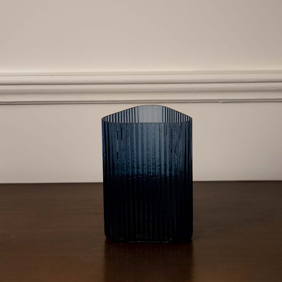 Deep blue ribbed glass vase for sophisticated home decor displays creating a vibrant pop of color on bedside table.