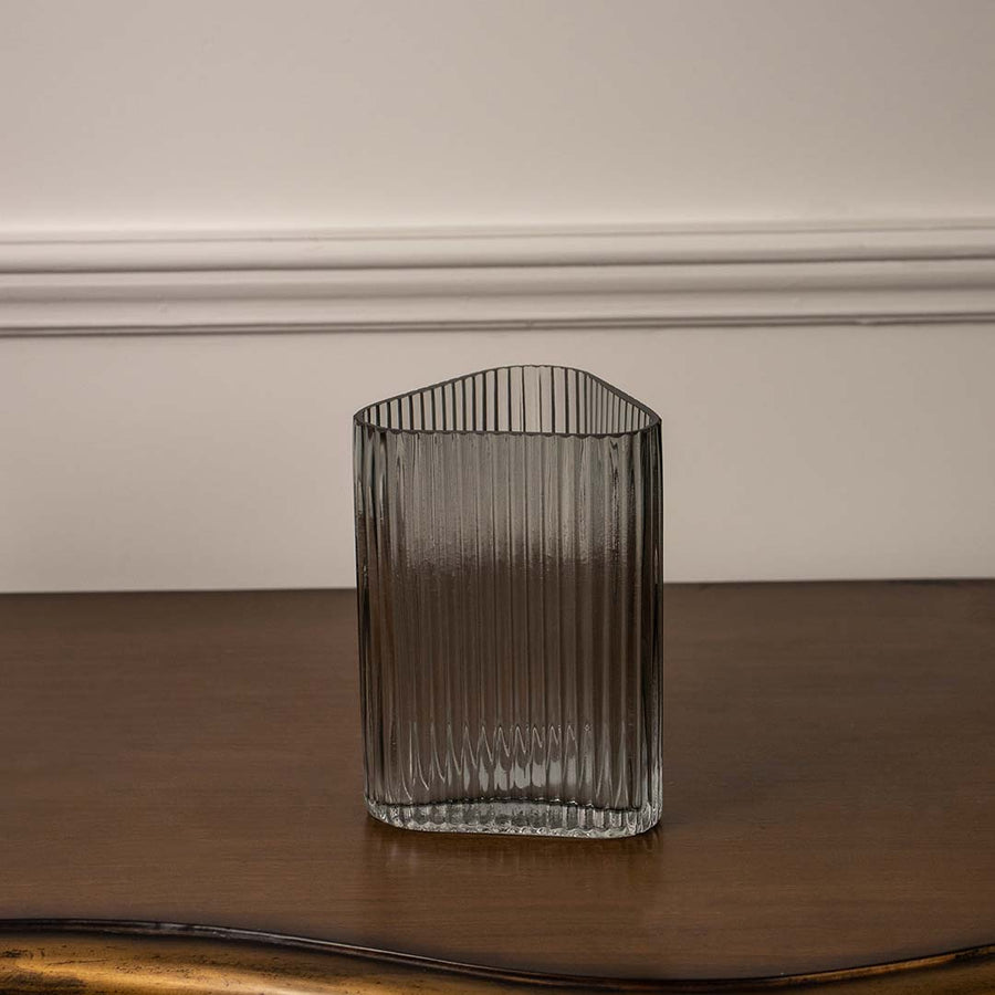 Elegant ribbed glass vase in neutral tone placed on wooden table for refined dining room interior styling accents.