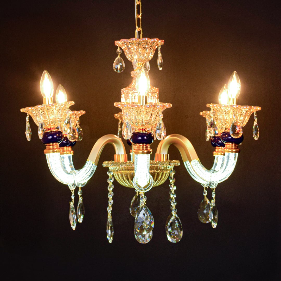 Gold and clear crystal chandelier glowing warmly on black background creating a dramatic luxury ceiling feature.