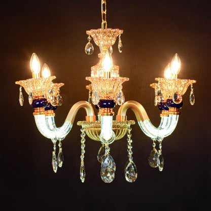 Gold and clear crystal chandelier glowing warmly on black background creating a dramatic luxury ceiling feature.