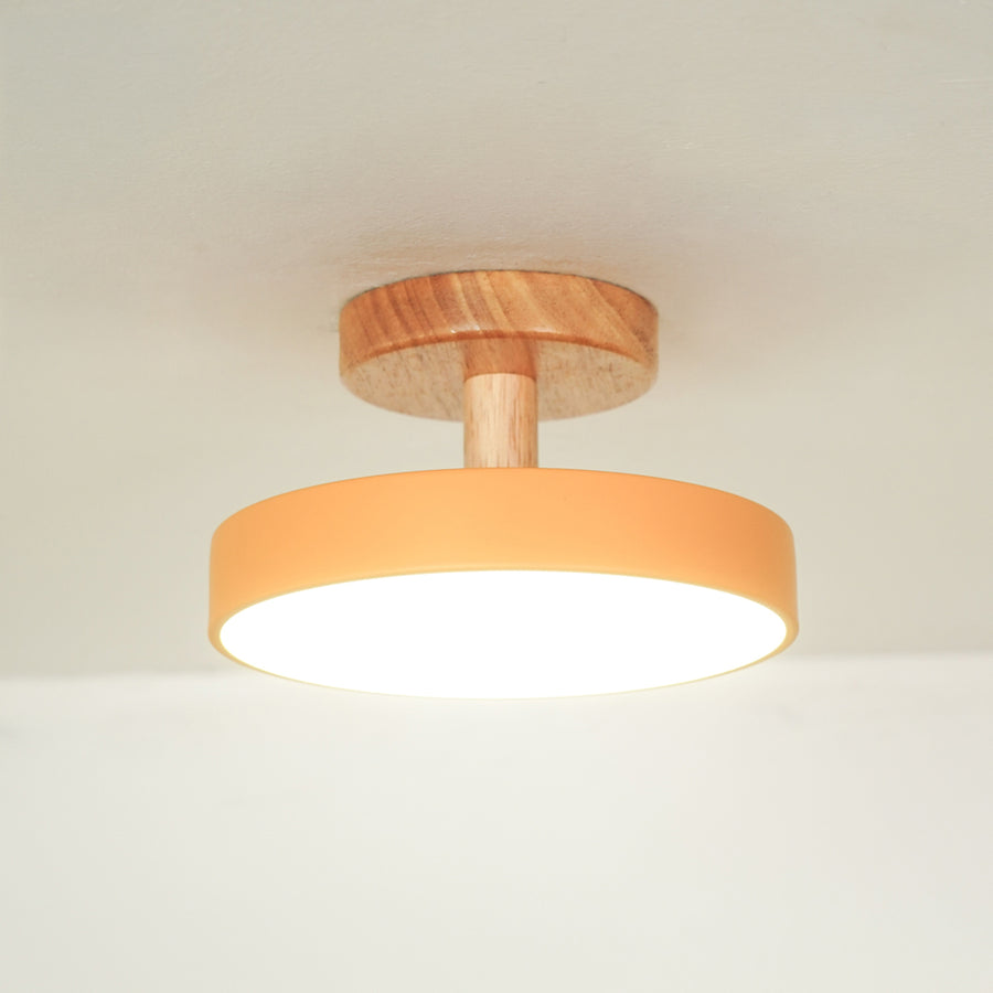 Closeup of peach metal and natural wood ceiling light for contemporary bedroom and Scandinavian decor styling spaces.
