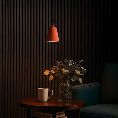 Terracotta cone pendant light turned off above a wooden side table with a vase of dried flowers and a ceramic mug in a cozy dark-toned corner.