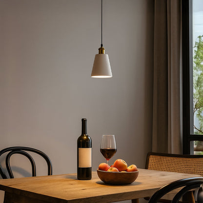 White cone pendant light glowing warmly above a wooden dining table with wine bottle and fruit bowl creating a cozy evening ambiance.
