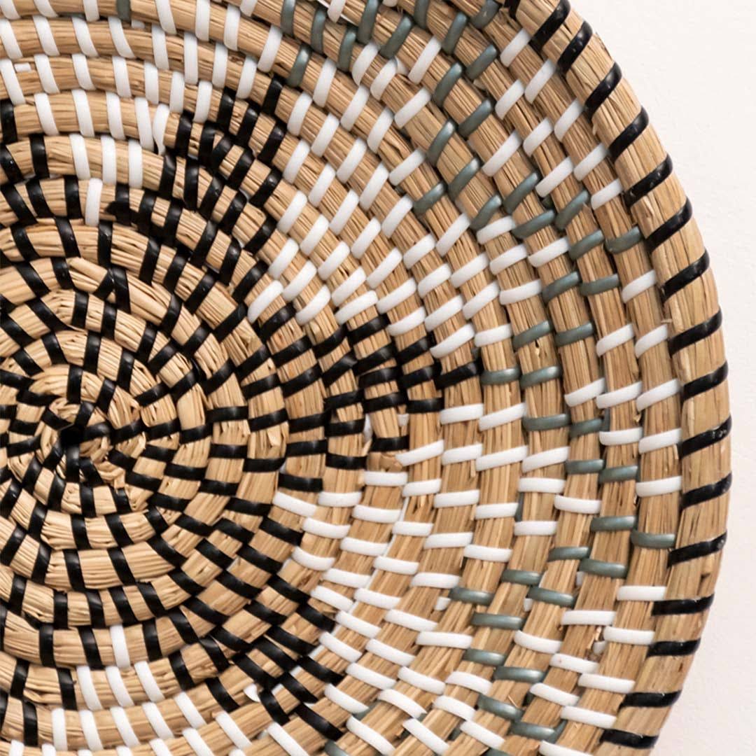 Close up view of a star pattern black and beige woven seagrass wall basket plate highlighting the detailed tight weave.