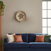 Decorative round wall art in neutral natural tones mounted above sofa creating balanced focal point and calm contemporary home styling.