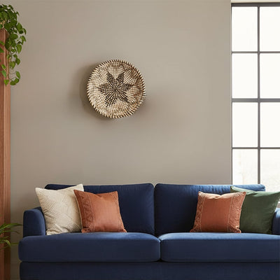 Decorative round wall art in neutral natural tones mounted above sofa creating balanced focal point and calm contemporary home styling.