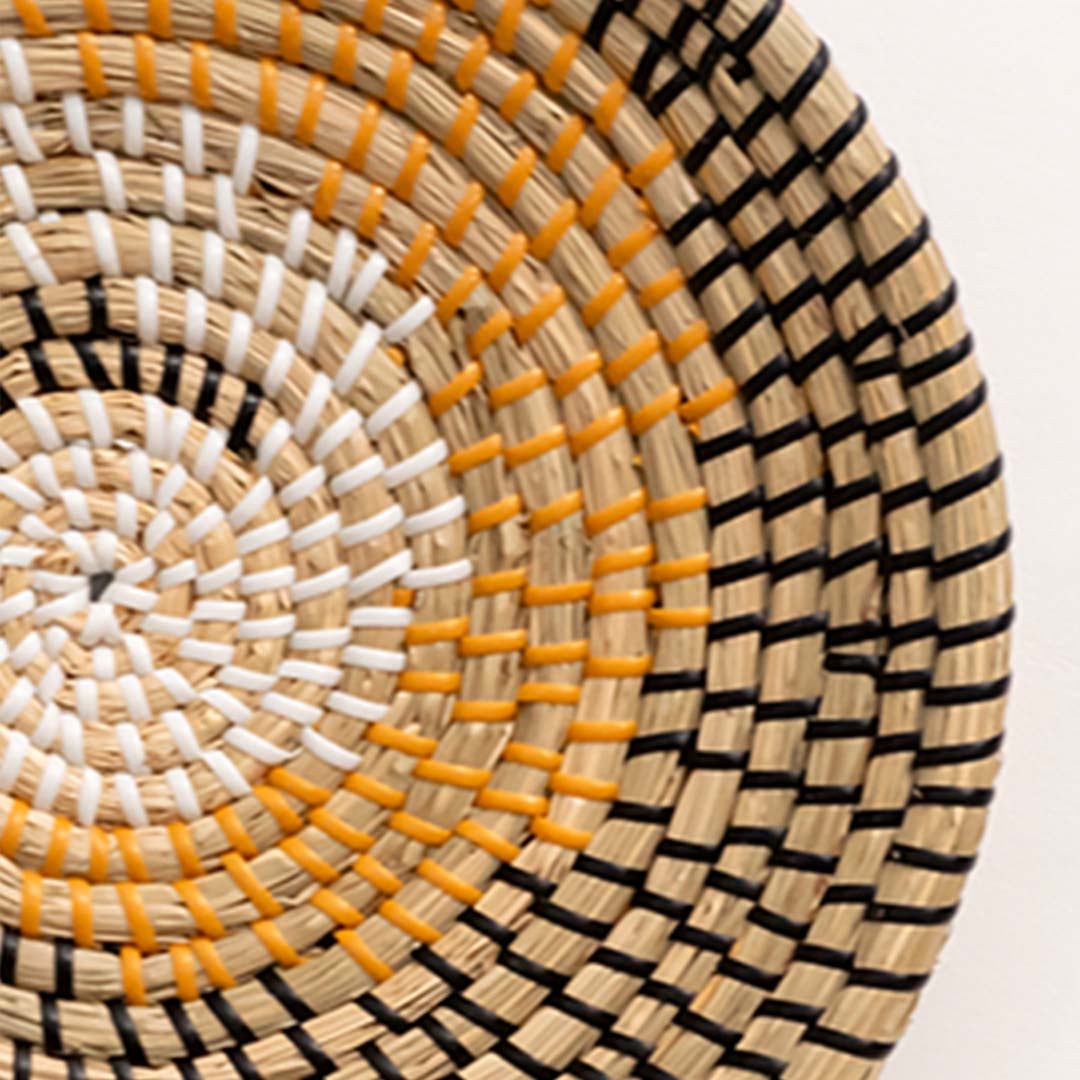 Closeup of yellow swirl handwoven basket wall decor showing detailed woven craftsmanship for boho interiors.