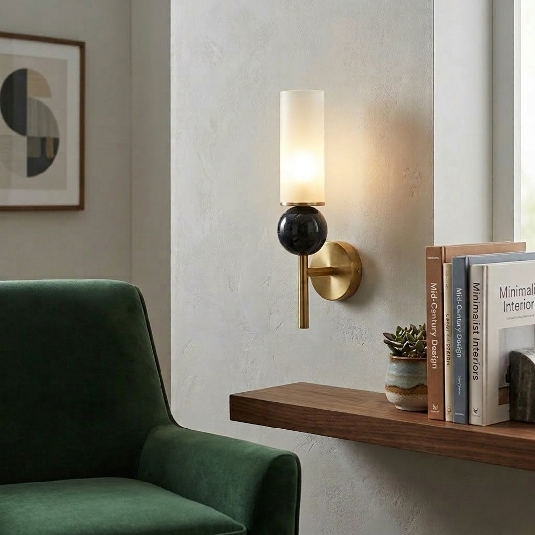 Modern wall sconce with black glass shade and gold metal arm installed beside wooden table in living room setting perfect for ambient lighting decor.