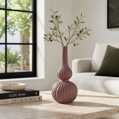 Pink textured ceramic flower vase with branches placed on modern coffee table in elegant living room decor.