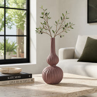 Pink textured ceramic flower vase with branches placed on modern coffee table in elegant living room decor.