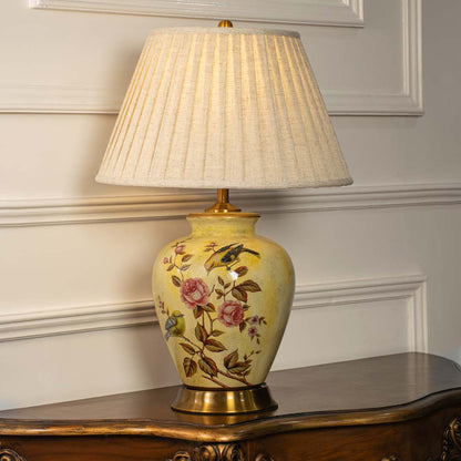 Yellow floral ceramic table lamp with pleated fabric shade styled on a wooden console table creating warm classic lighting.