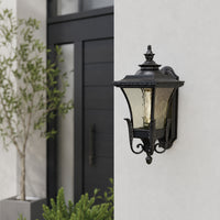 Traditional black metal outdoor post lantern for gate entrance garden pathway and landscape with warm ambient lighting.