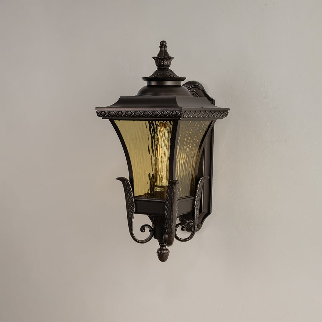 Bronze metal outdoor wall light on white background with 54 cm height and amber ripple glass shade for patio decor.