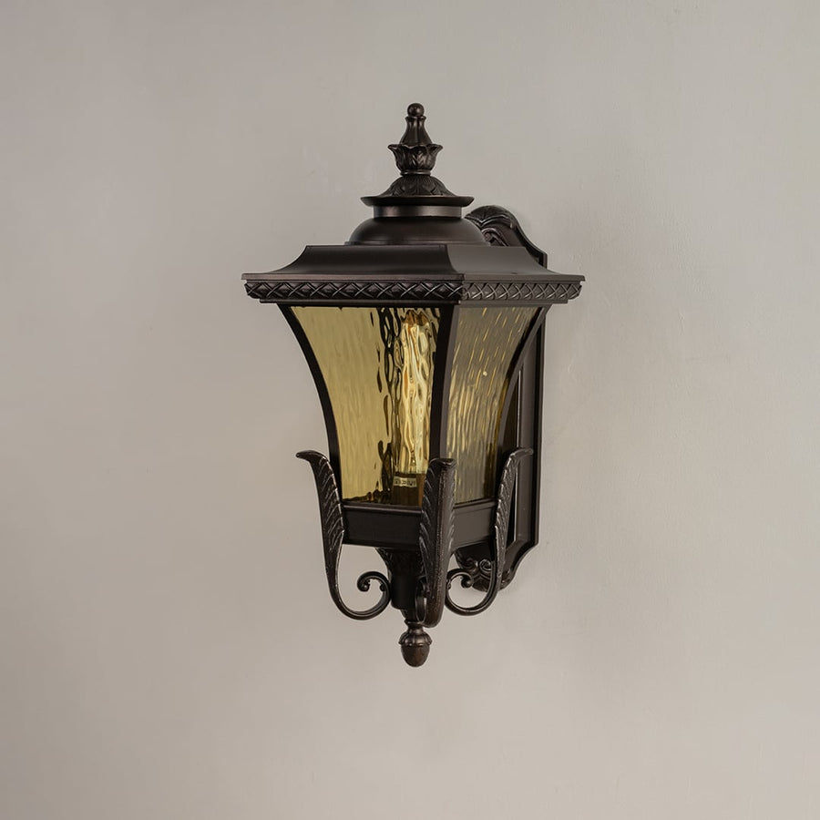 Bronze metal outdoor wall light on white background with 54 cm height and amber ripple glass shade for patio decor.