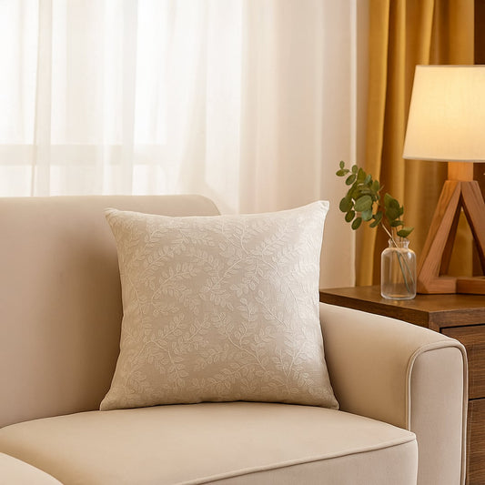 Main lifestyle image of elegant beige cushion cover with subtle leaf pattern placed on sofa creating warm cozy living room decor ambiance.