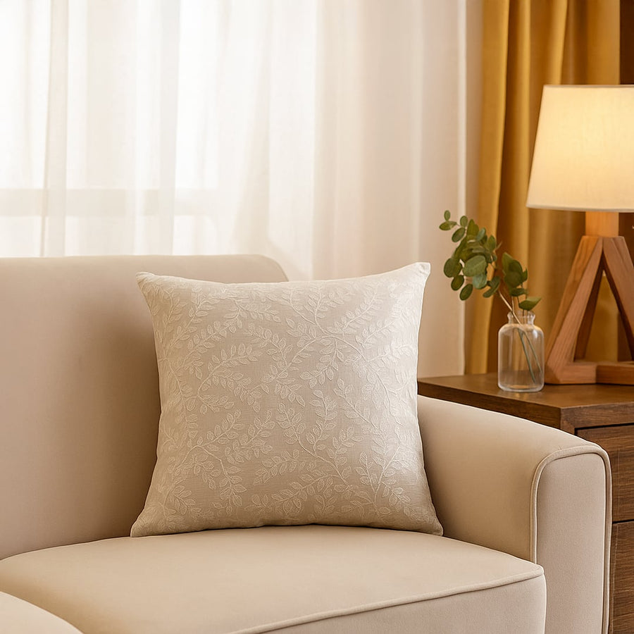 Main lifestyle image of elegant beige cushion cover with subtle leaf pattern placed on sofa creating warm cozy living room decor ambiance.