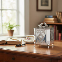 Silver metal decorative storage box with embossed detailing and bird handle styled on console adding vintage charm to home Decor.