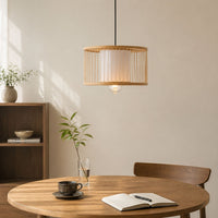 Modern bamboo grid drum pendant light fixture with white fabric shade hanging above a round wooden dining table for Japandi kitchen decor.