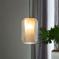 Contemporary frosted white glass pendant light glowing in a modern dining room setup near green indoor plants for ambiance.