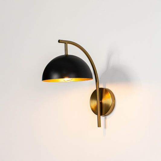 Industrial wall light in black and gold metal finish with dome shade for bedroom or living decor lighting placement white background.