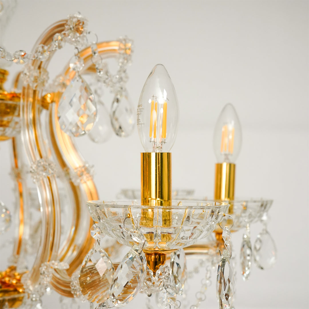 Closeup image of eight light gold transparent crystal chandelier for elegant ceiling decor styling with reflective finish.