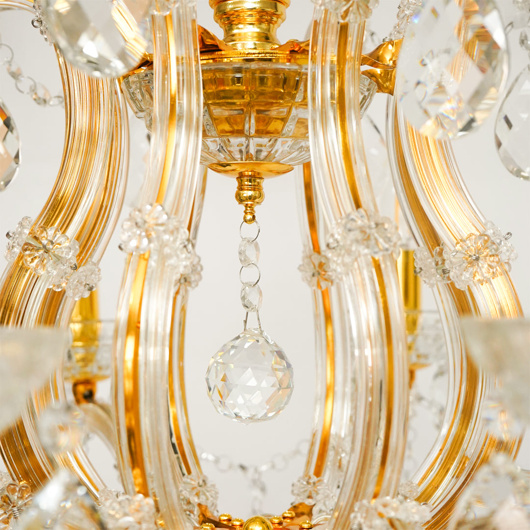 Closeup image of eight light gold transparent crystal chandelier for modern ceiling decor styling with reflective finish.