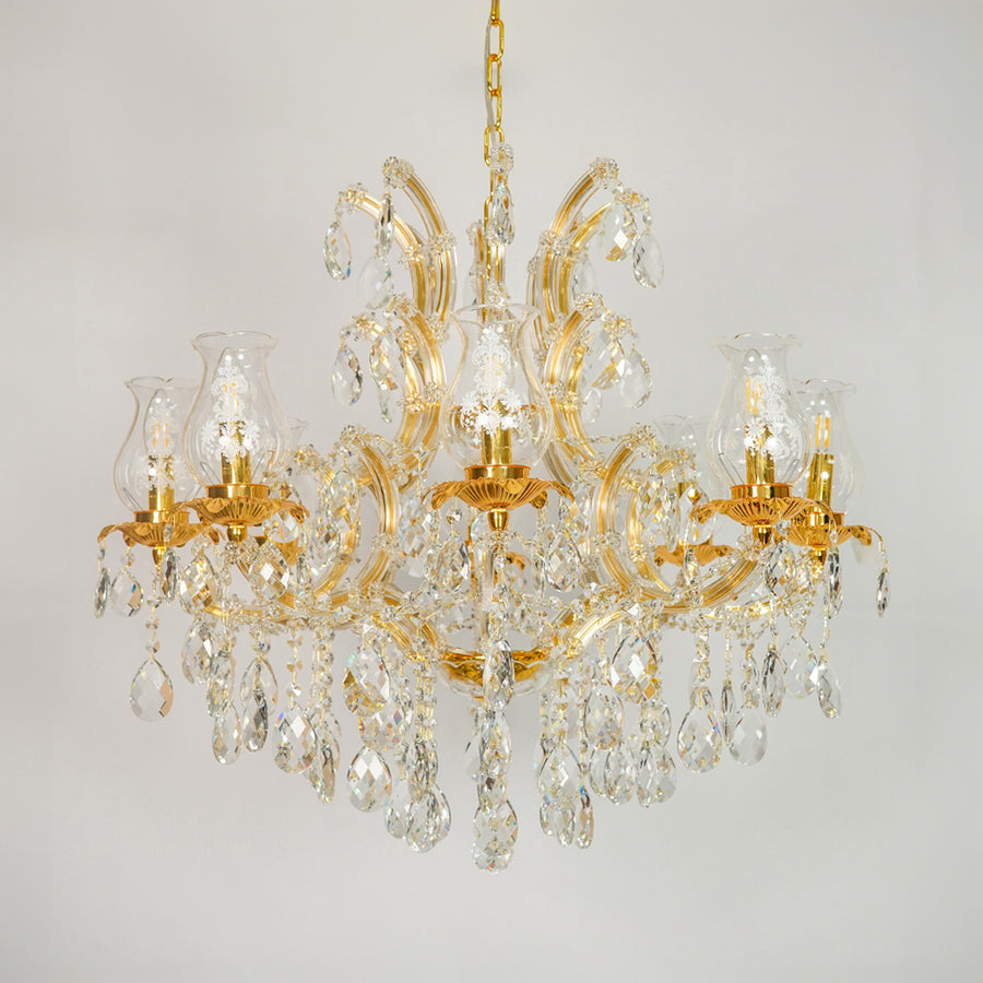 A classic multi-arm chandelier with a polished gold-finished metal frame and numerous clear crystal prisms and hanging drops, shown against a neutral light gray background.