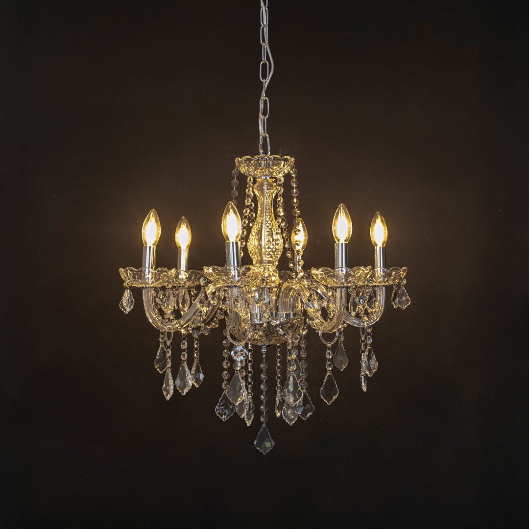 Elegant chandelier with silver frame and crystal droplets illuminated against black background for decor.
