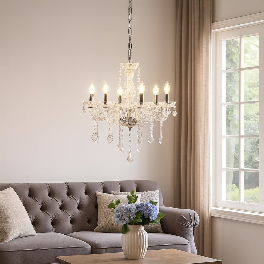 Crystal chandelier with silver accents glowing warmly above sofa in living room for luxury home lighting.