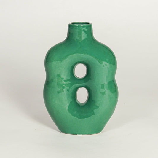 Modern green ceramic decorative vase with sculptural form and glossy glaze isolated on white background.